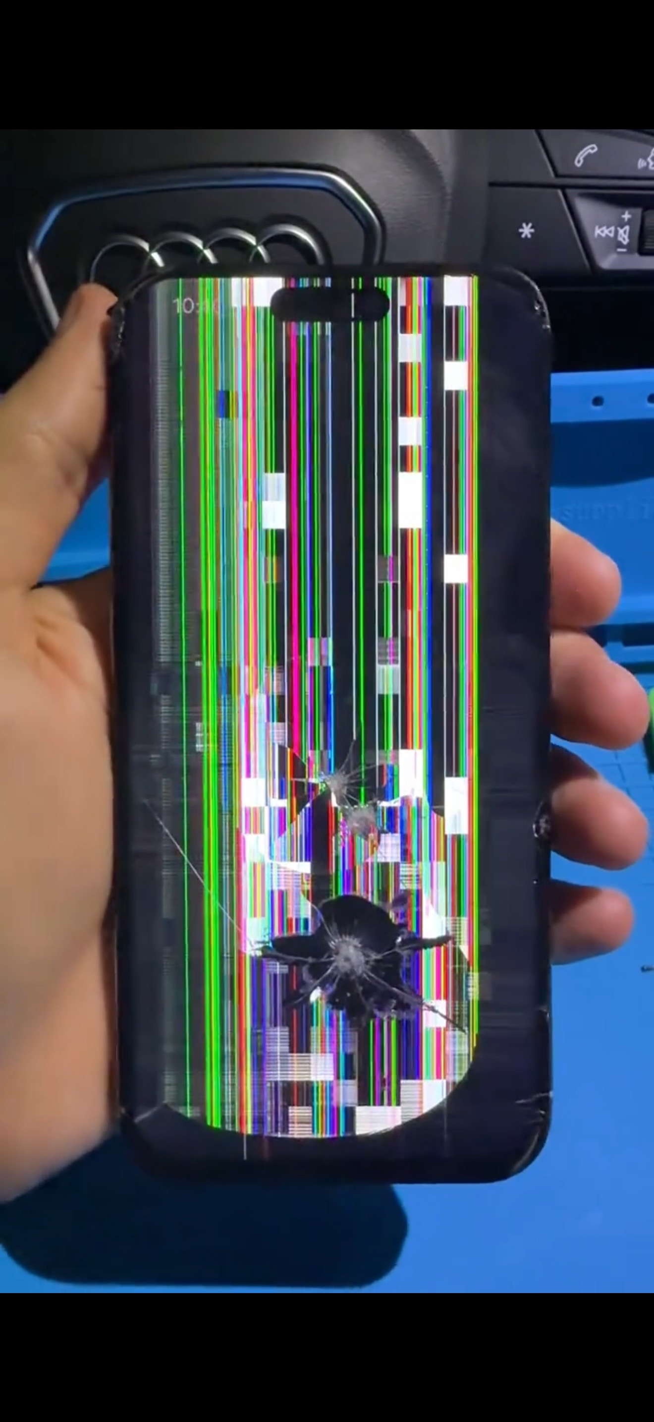 Before repair: iPhone display heavily damaged with colored vertical lines and cracked glass